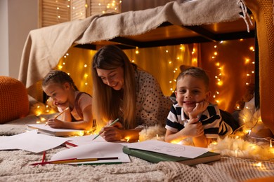 Mother and her children drawing in play tent at home
