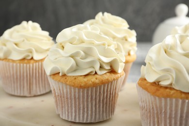 Tasty cupcakes with vanilla cream on table, closeup