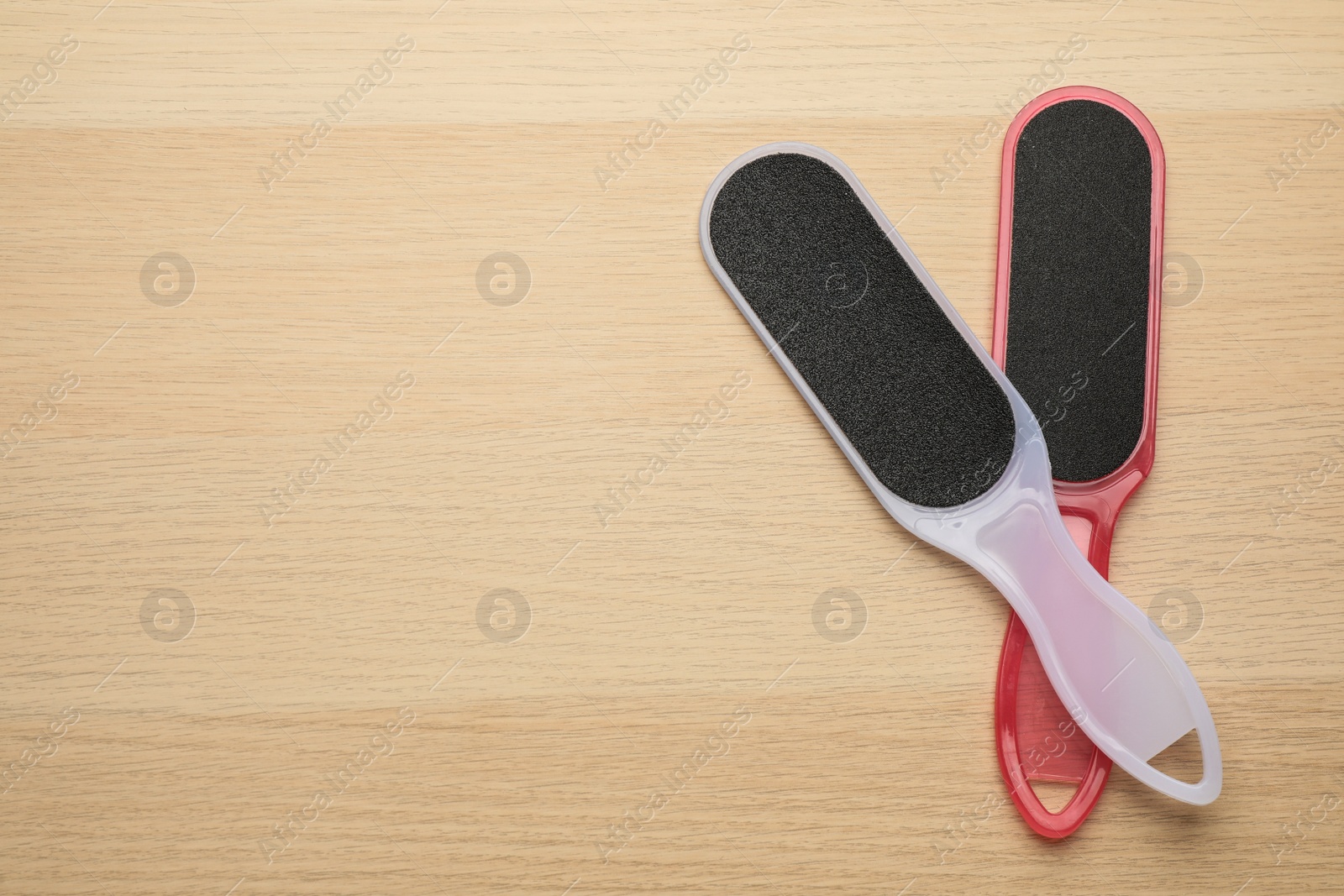Photo of Colorful foot files on wooden table, flat lay with space for text. Pedicure tools