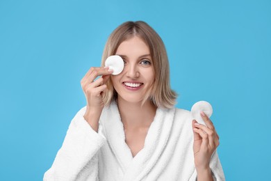 Young woman with cotton pads on light blue background