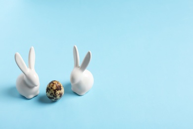 Ceramic Easter bunnies and egg on color background, space for text