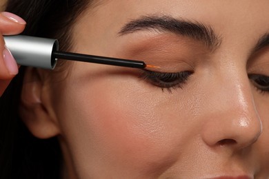 Photo of Woman applying serum onto her eyelashes, closeup. Cosmetic product