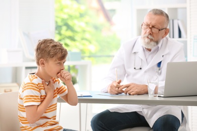 Photo of Coughing little boy visiting doctor at clinic