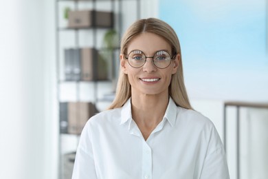 Photo of Portrait of beautiful businesswoman in glasses indoors. Confident lady with blonde hair looking into camera