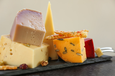 Photo of Different delicious cheeses on slate plate, closeup