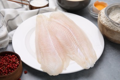 Photo of Different ingredients for batter and raw fish fillet on light grey table