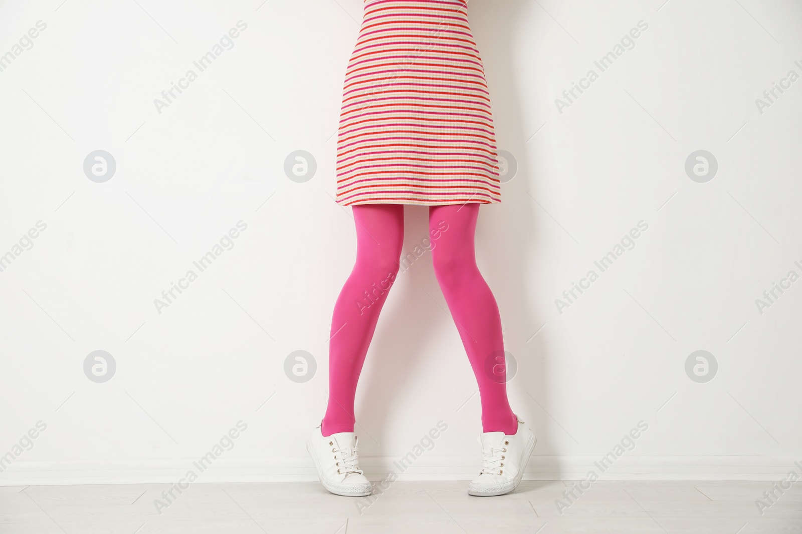 Photo of Woman wearing pink tights near white wall, closeup