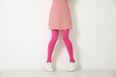 Woman wearing pink tights near white wall, closeup