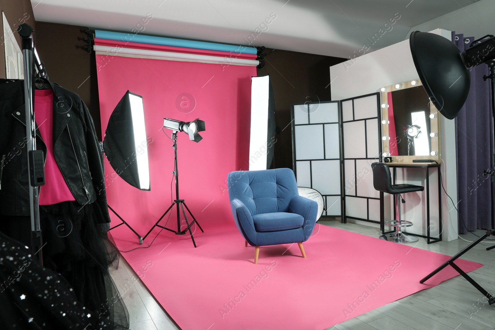 Photo of Stylish blue armchair in photo studio with professional equipment