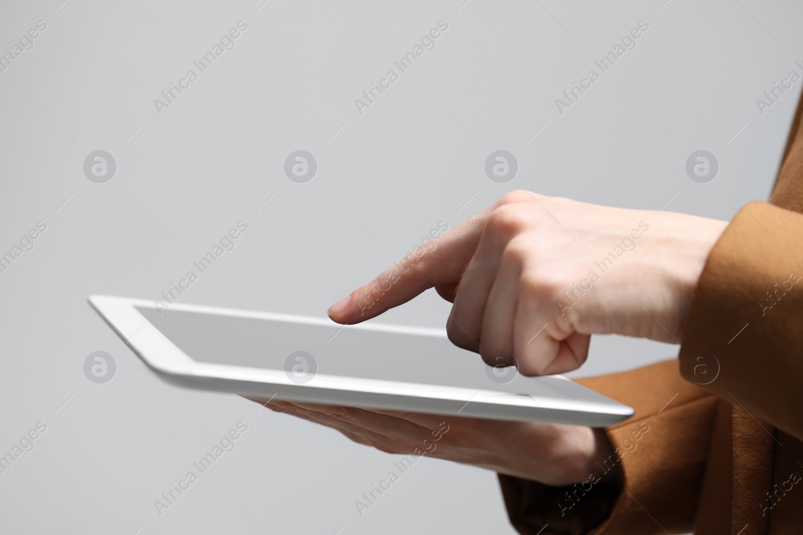 Photo of Closeup view of woman using modern tablet on grey background