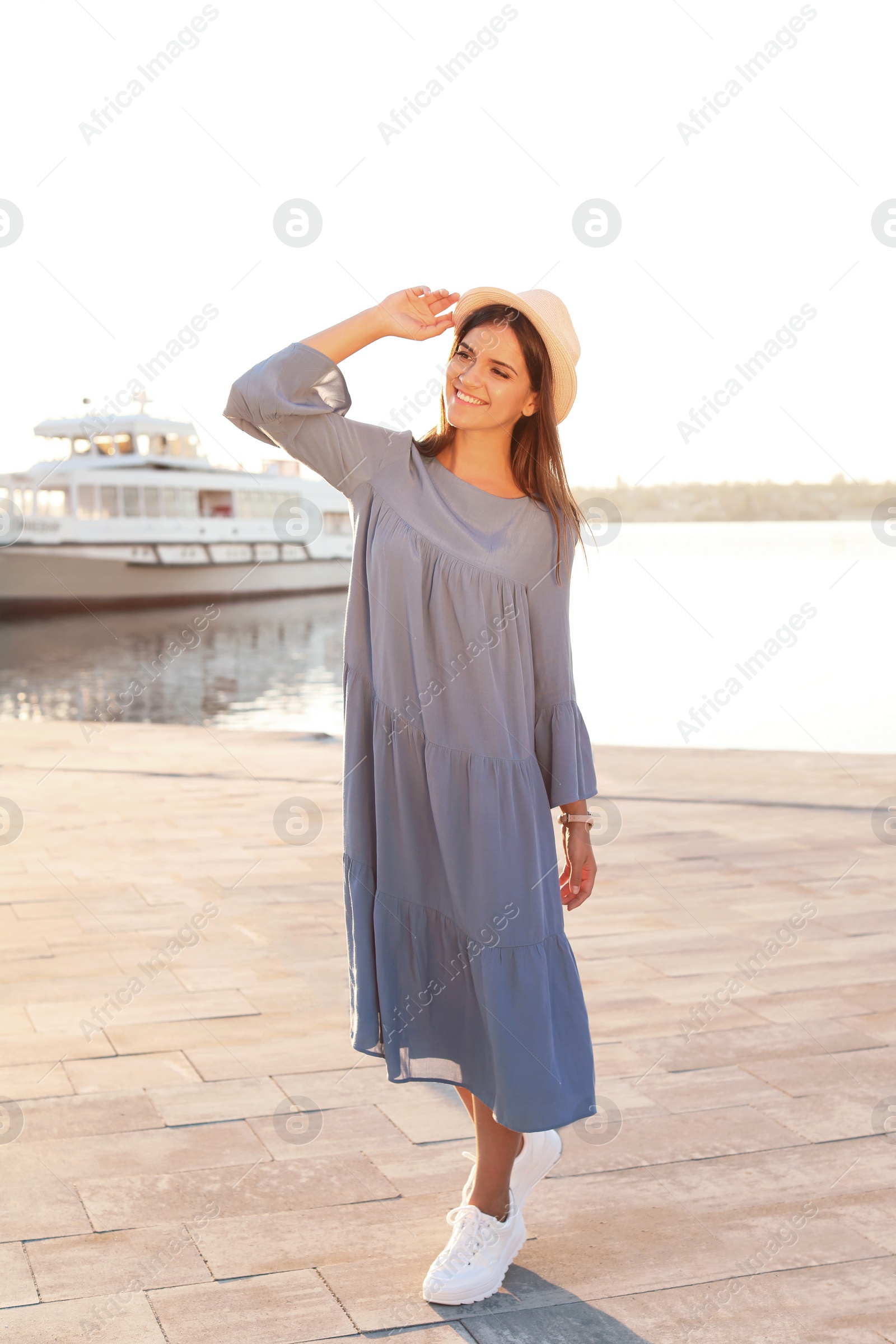 Photo of Young woman walking on pier at sunset light