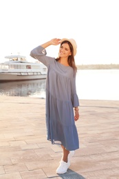 Photo of Young woman walking on pier at sunset light