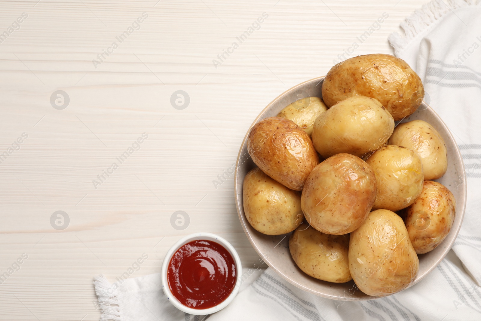 Photo of Delicious baked potatoes and tomato sauce on white wooden table, top view. Space for text