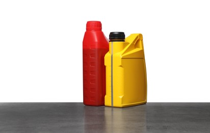 Photo of Motor oil in different containers on grey table against white background