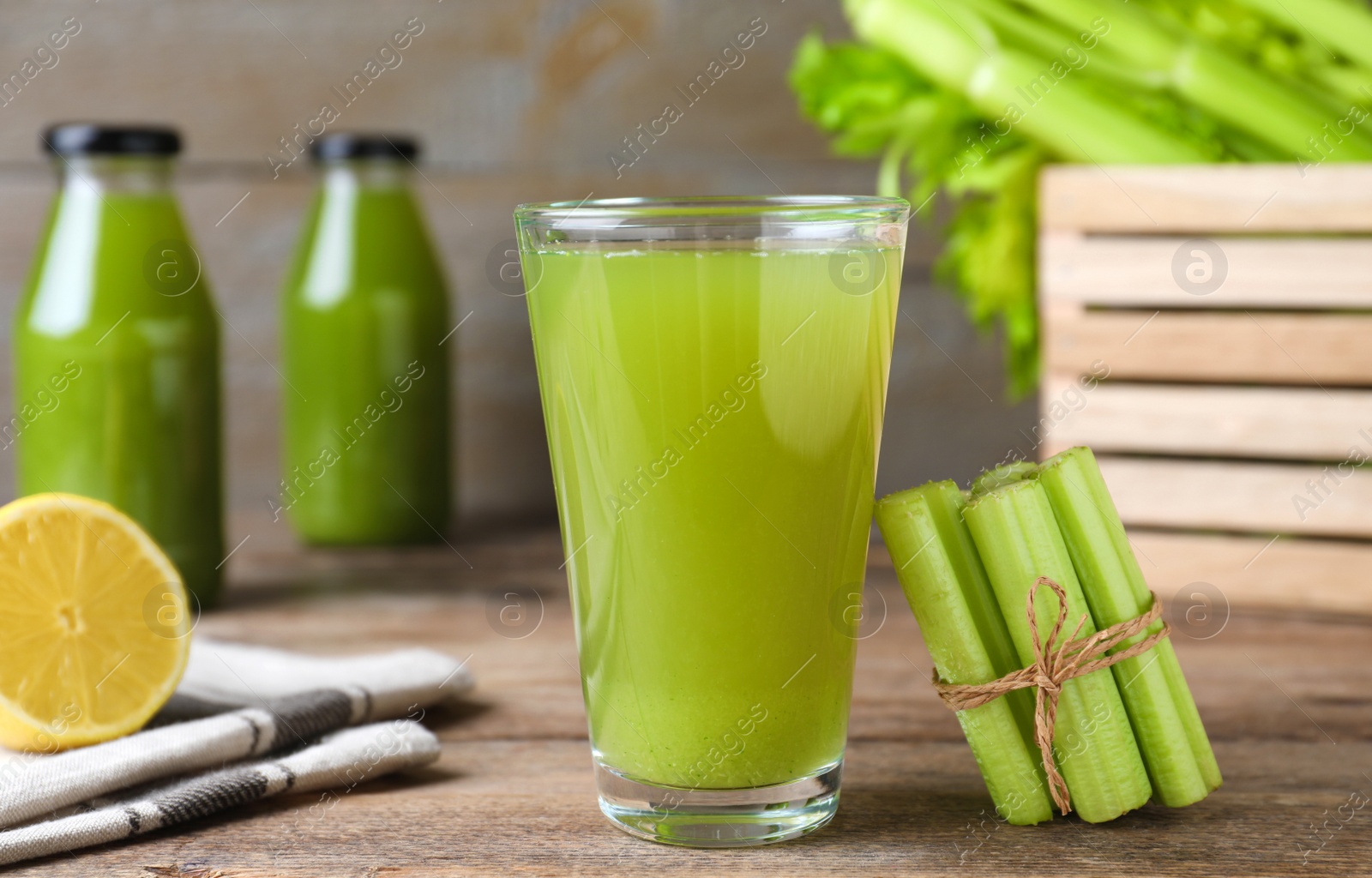 Photo of Fresh celery and glass of juice on wooden table, closeup