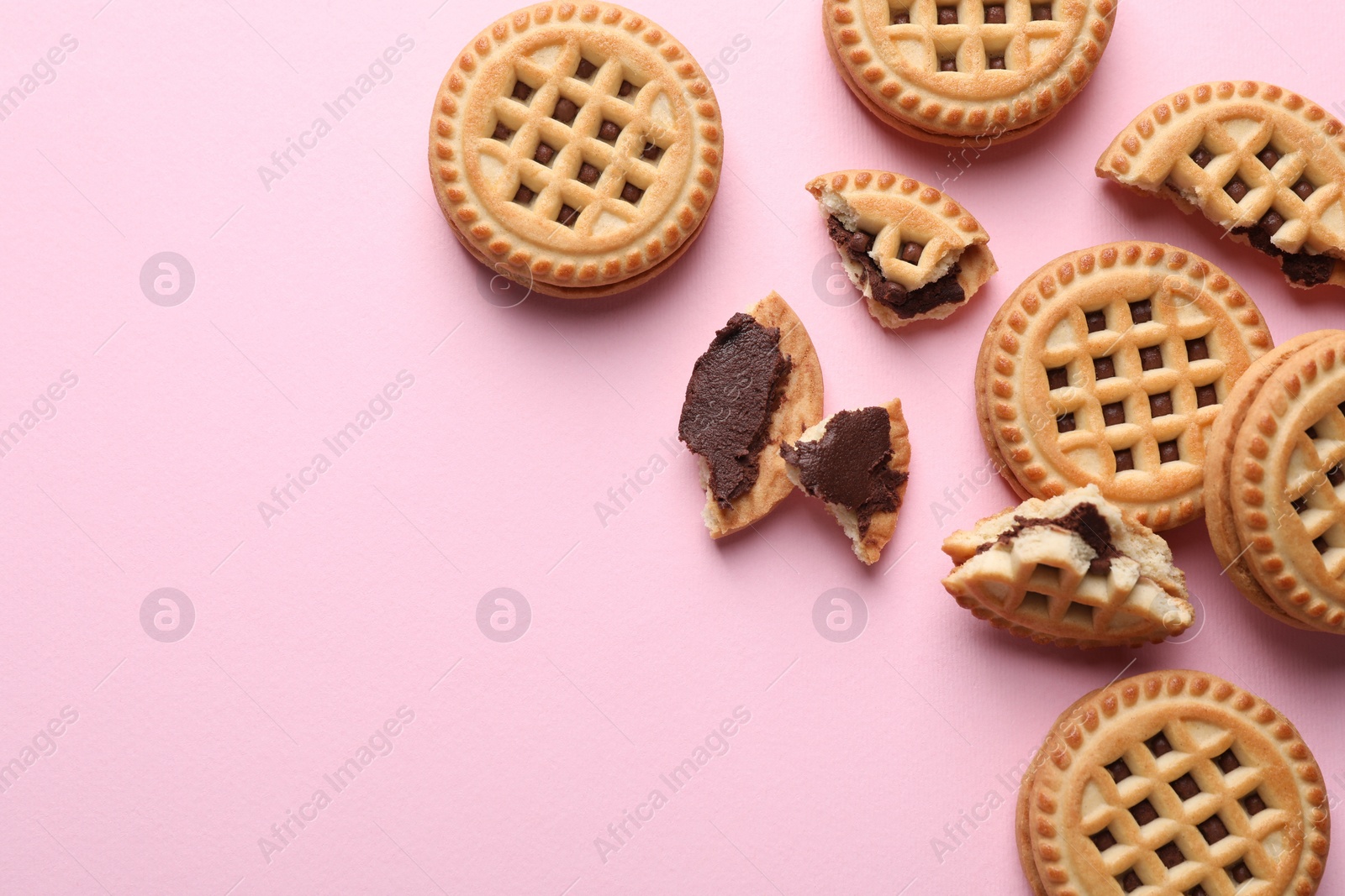 Photo of Tasty sandwich cookies with cream on pink background, flat lay. Space for text