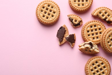 Photo of Tasty sandwich cookies with cream on pink background, flat lay. Space for text