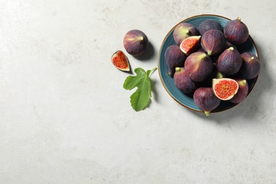 Photo of Plate with fresh ripe figs and green leaf on light table, flat lay. Space for text