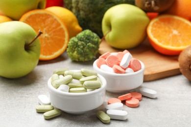 Photo of Dietary supplements. Different pills in bowls and food products on grey table