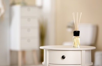 Aromatic reed air freshener on table against blurred background