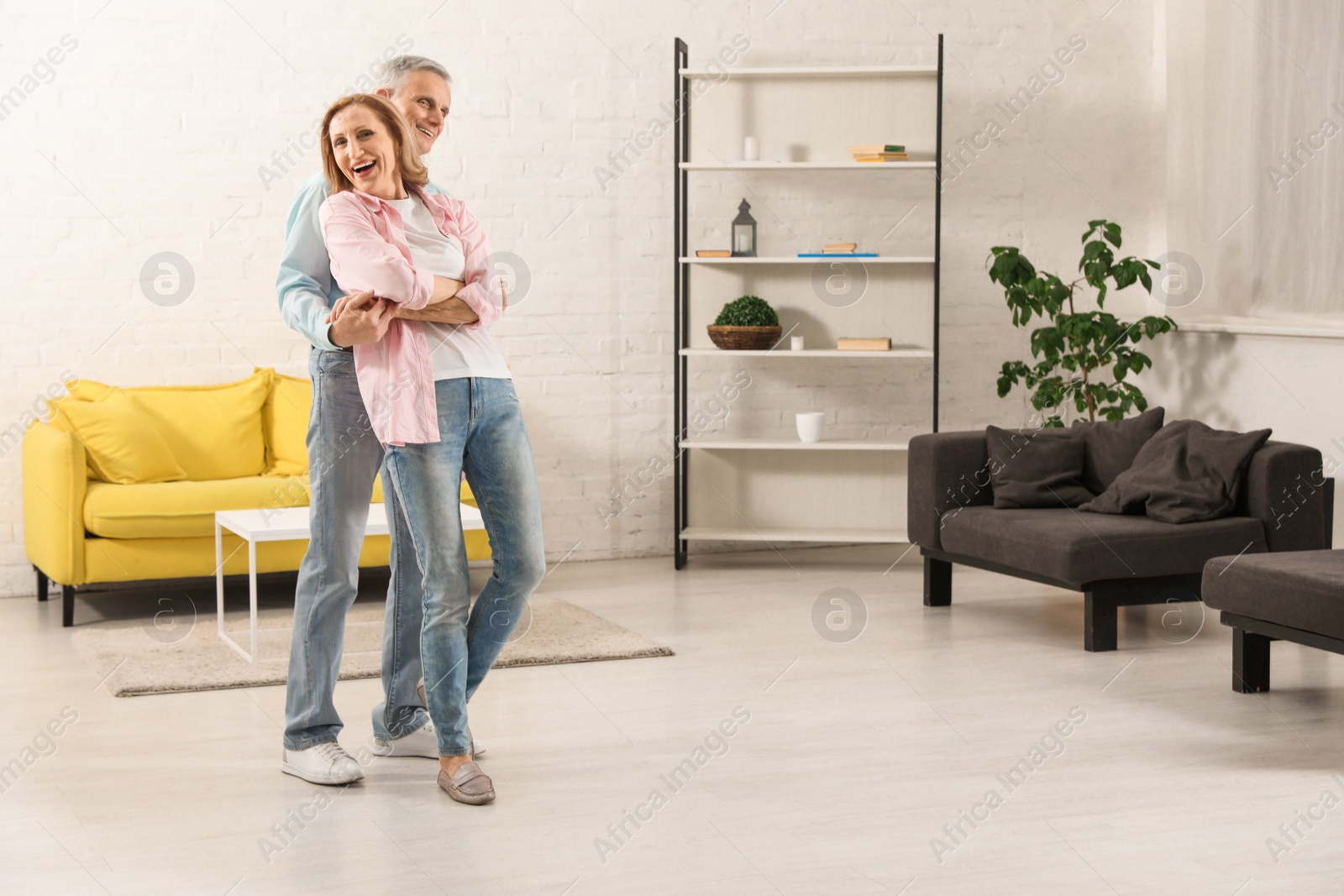 Photo of Happy senior couple dancing together in living room