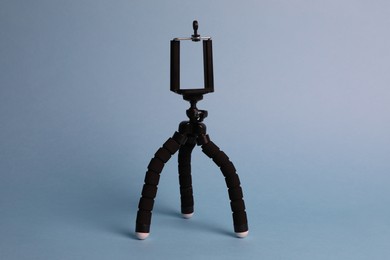 Photo of Modern stylish mobile tripod on light blue background