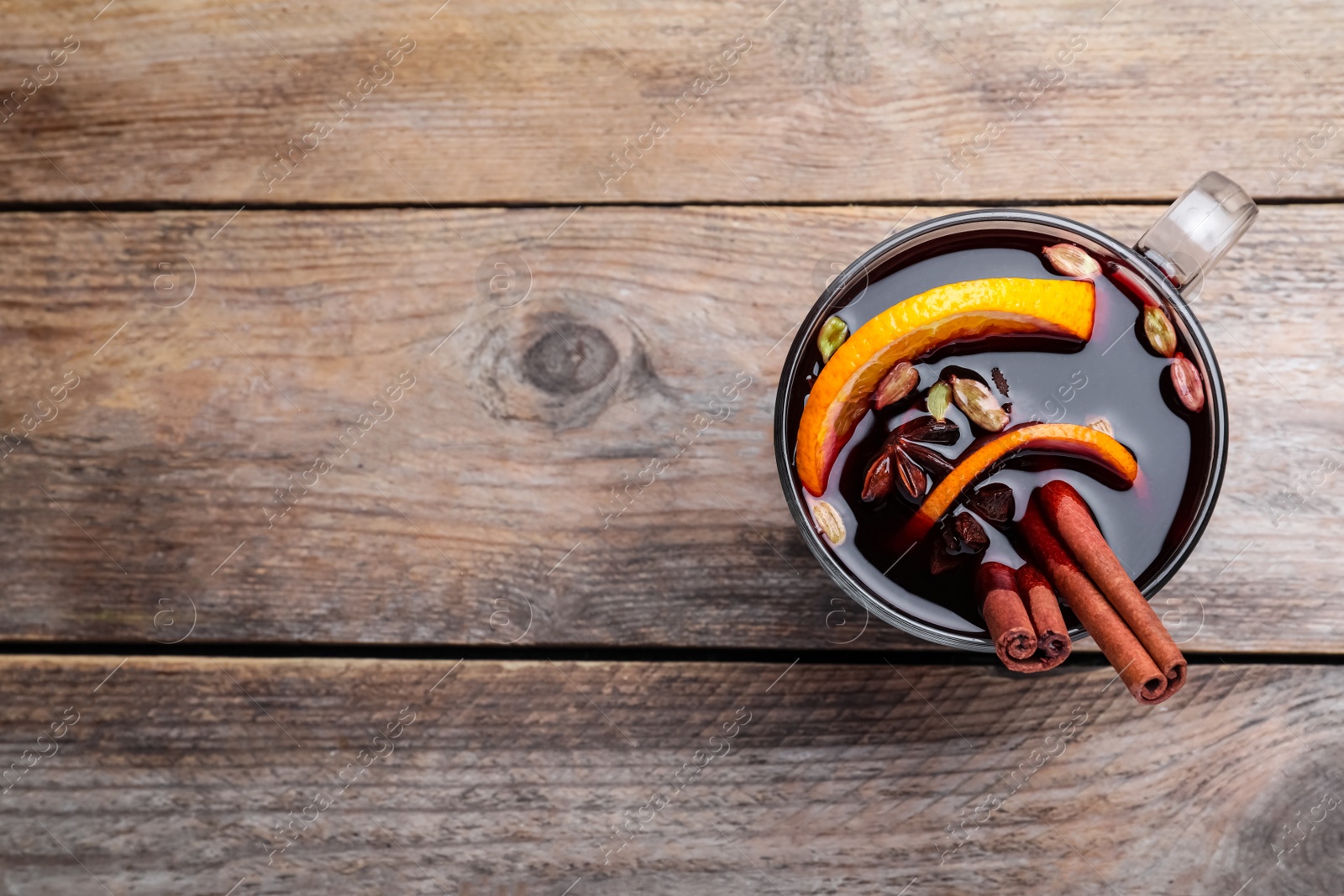 Photo of Aromatic mulled wine on wooden table, top view. Space for text