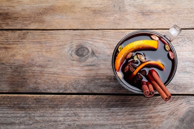 Aromatic mulled wine on wooden table, top view. Space for text