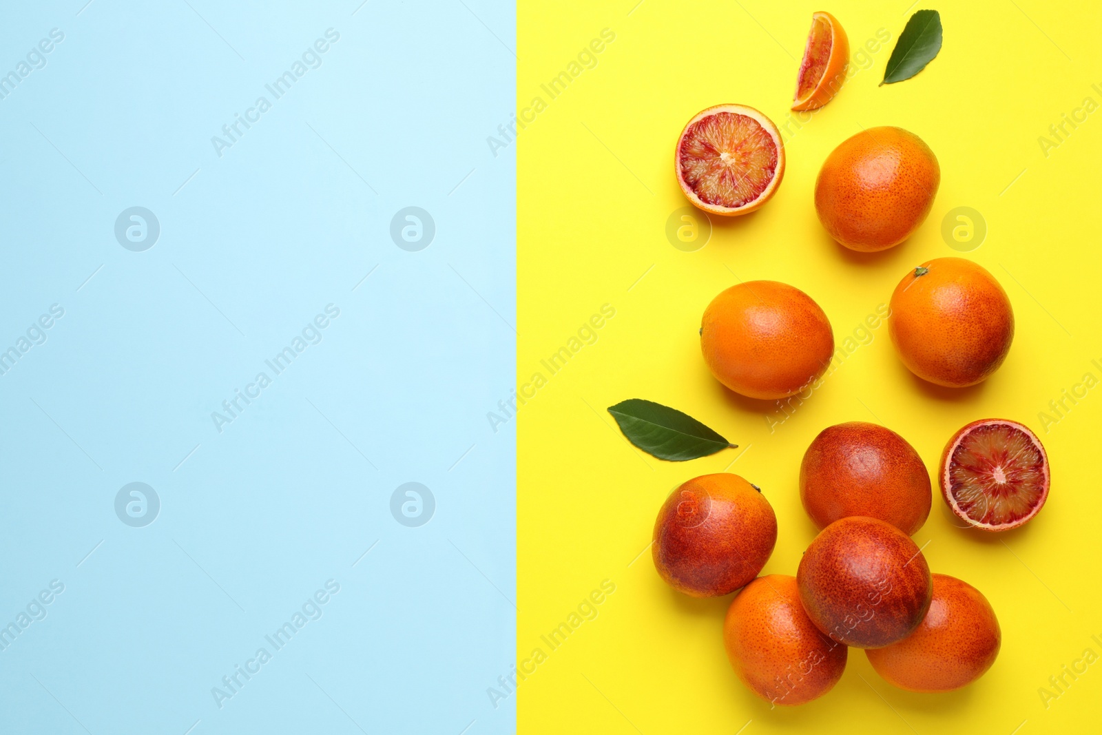 Photo of Many ripe sicilian oranges and leaves on color background, flat lay. Space for text