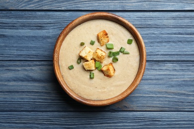 Photo of Bowl of fresh homemade mushroom soup on wooden background, top view