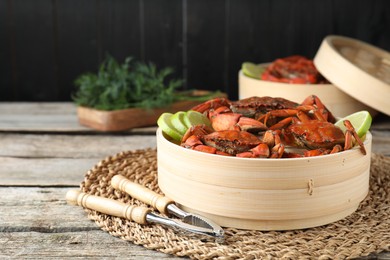 Photo of Delicious boiled crabs with lime and dill served on wooden table, space for text