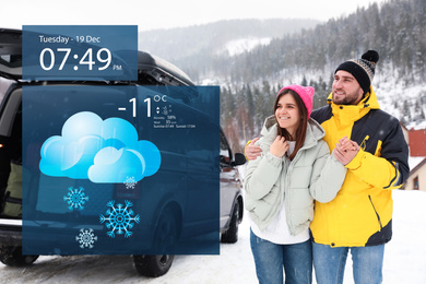 Happy couple near car on snowy road and weather forecast widget. Mobile application