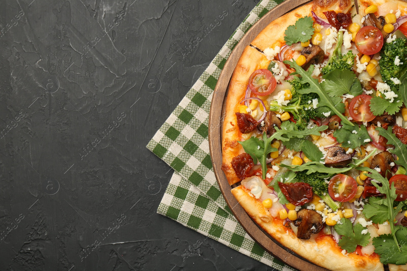 Photo of Delicious vegetarian pizza with cheese, mushrooms, vegetables and greens on black table, top view. Space for text