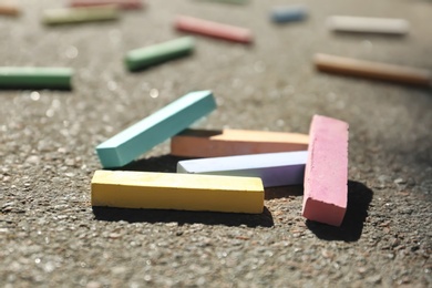 Photo of Many colorful chalk sticks on asphalt, closeup