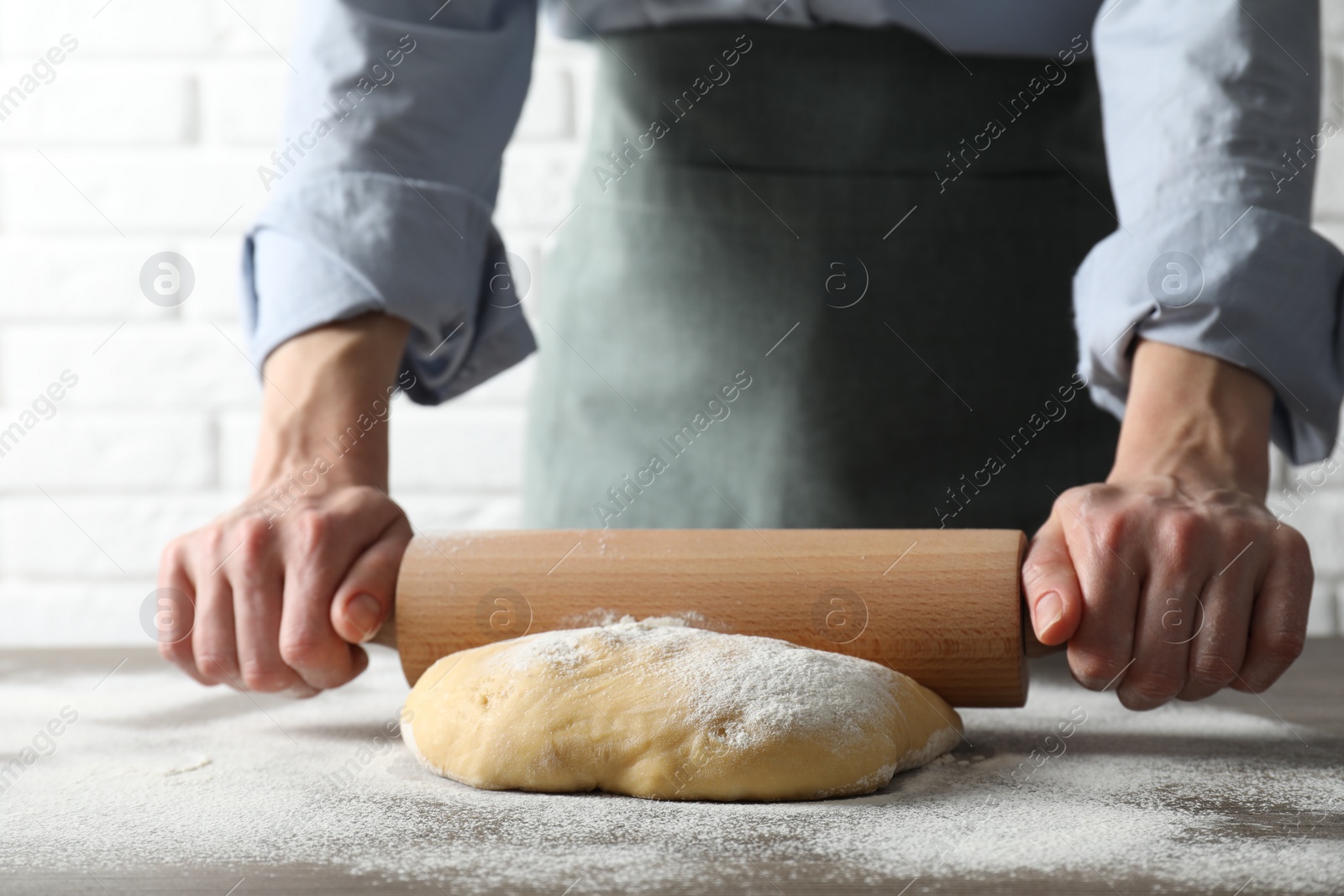 Photo of Woman rolling raw dough at table, closeup