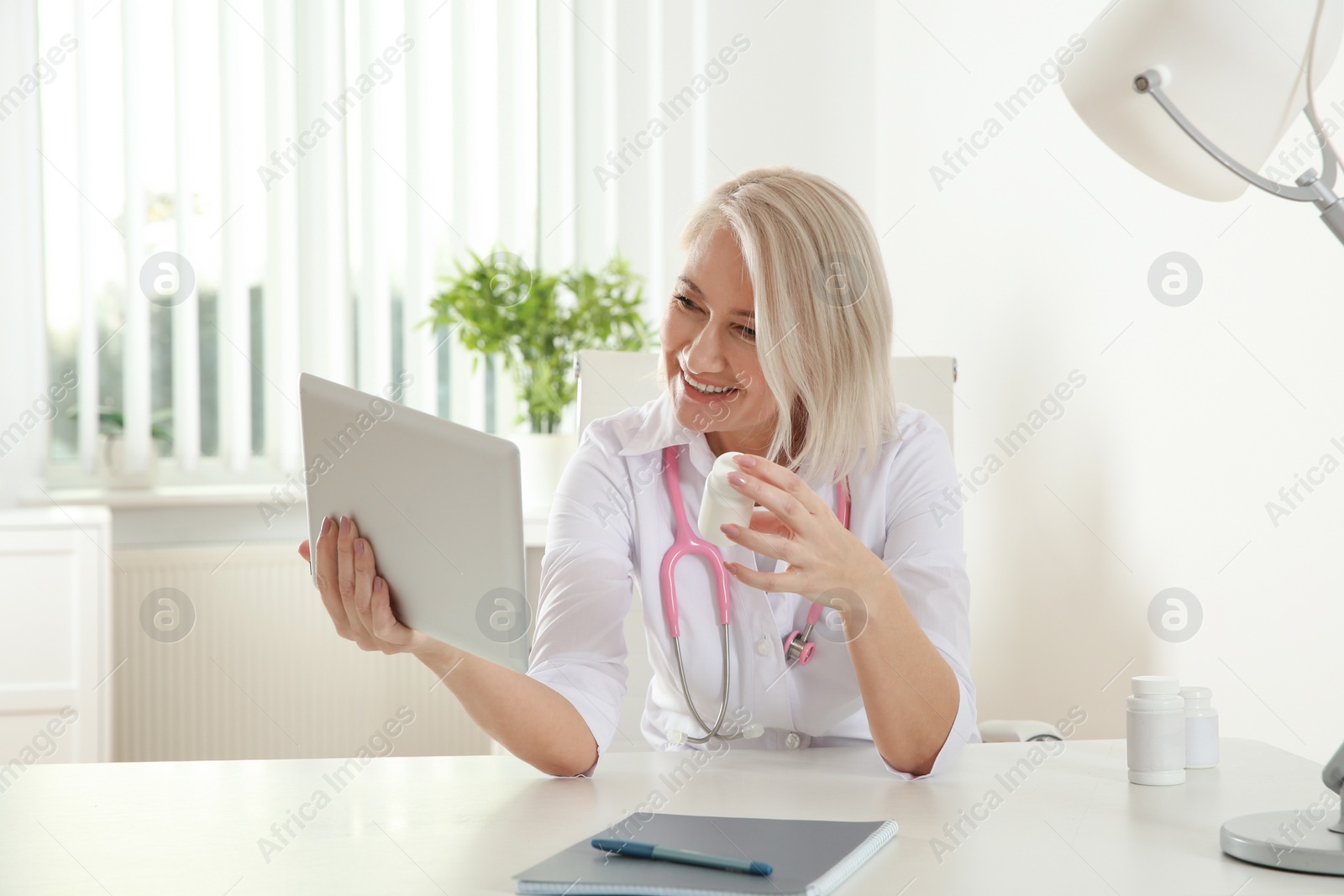 Photo of Doctor consulting patient using video chat on tablet in clinic