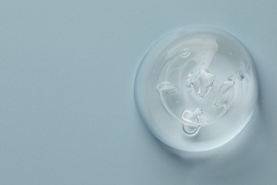 Photo of Sample of clear cosmetic gel on light blue background, top view. Space for text