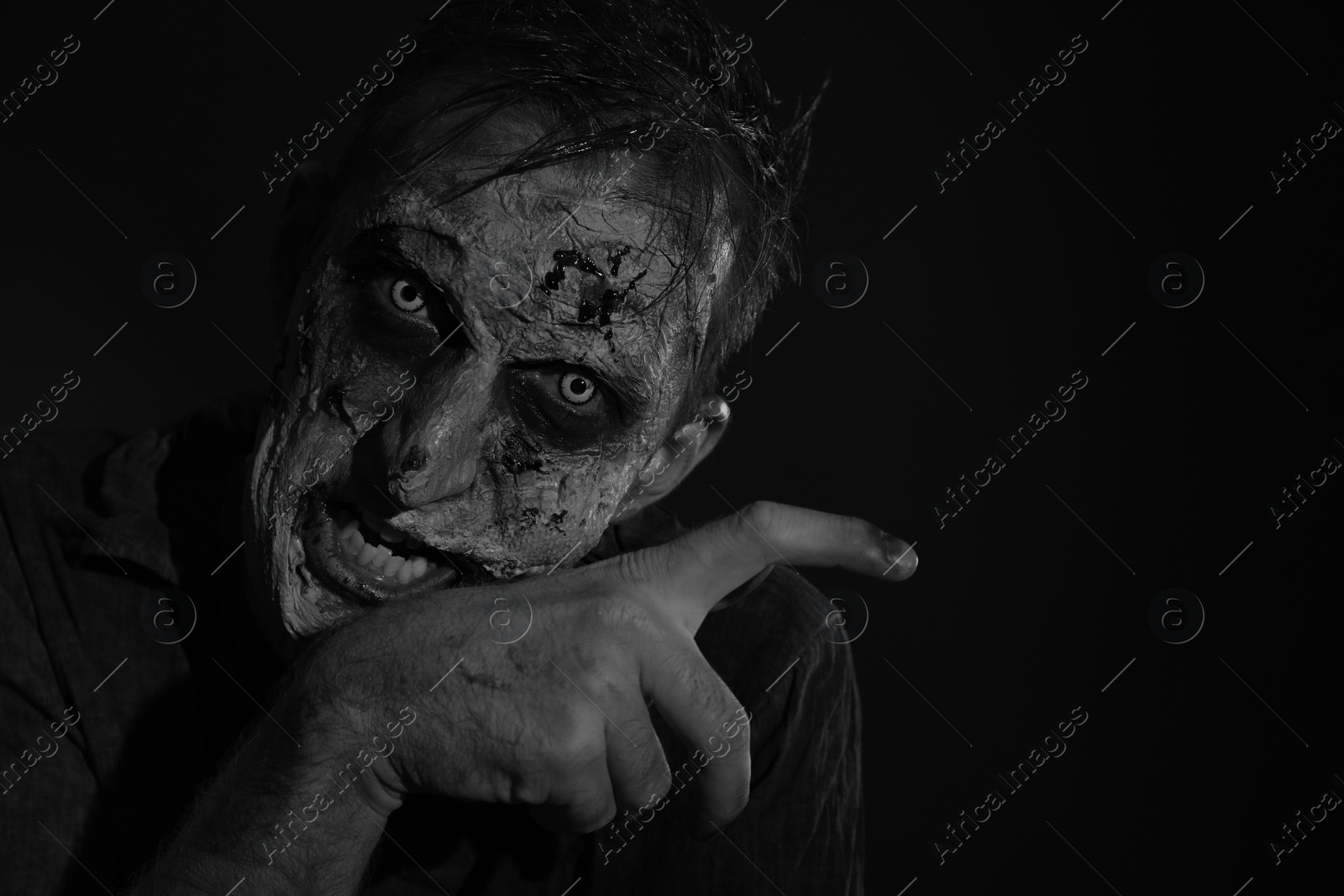 Photo of Scary zombie on dark background, black and white effect. Halloween monster