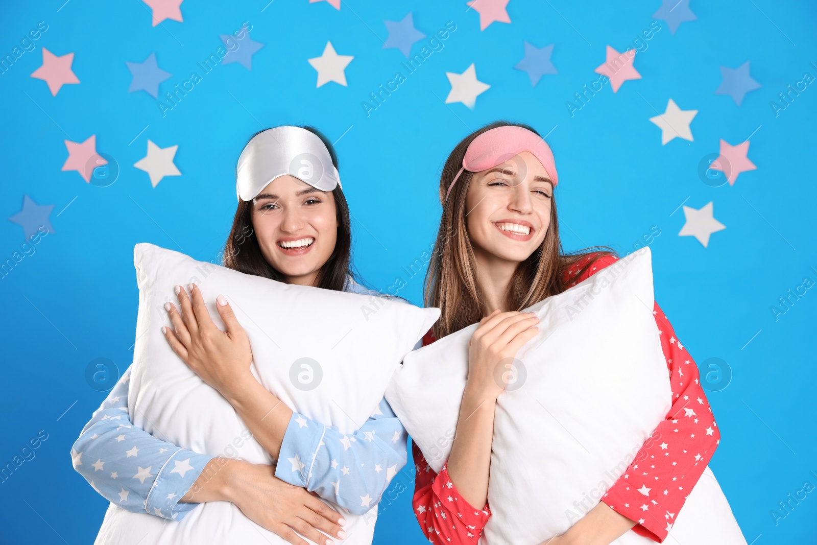 Photo of Beautiful women with pillows on light blue background. Bedtime