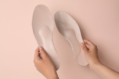 Woman holding orthopedic insoles on pink background, closeup