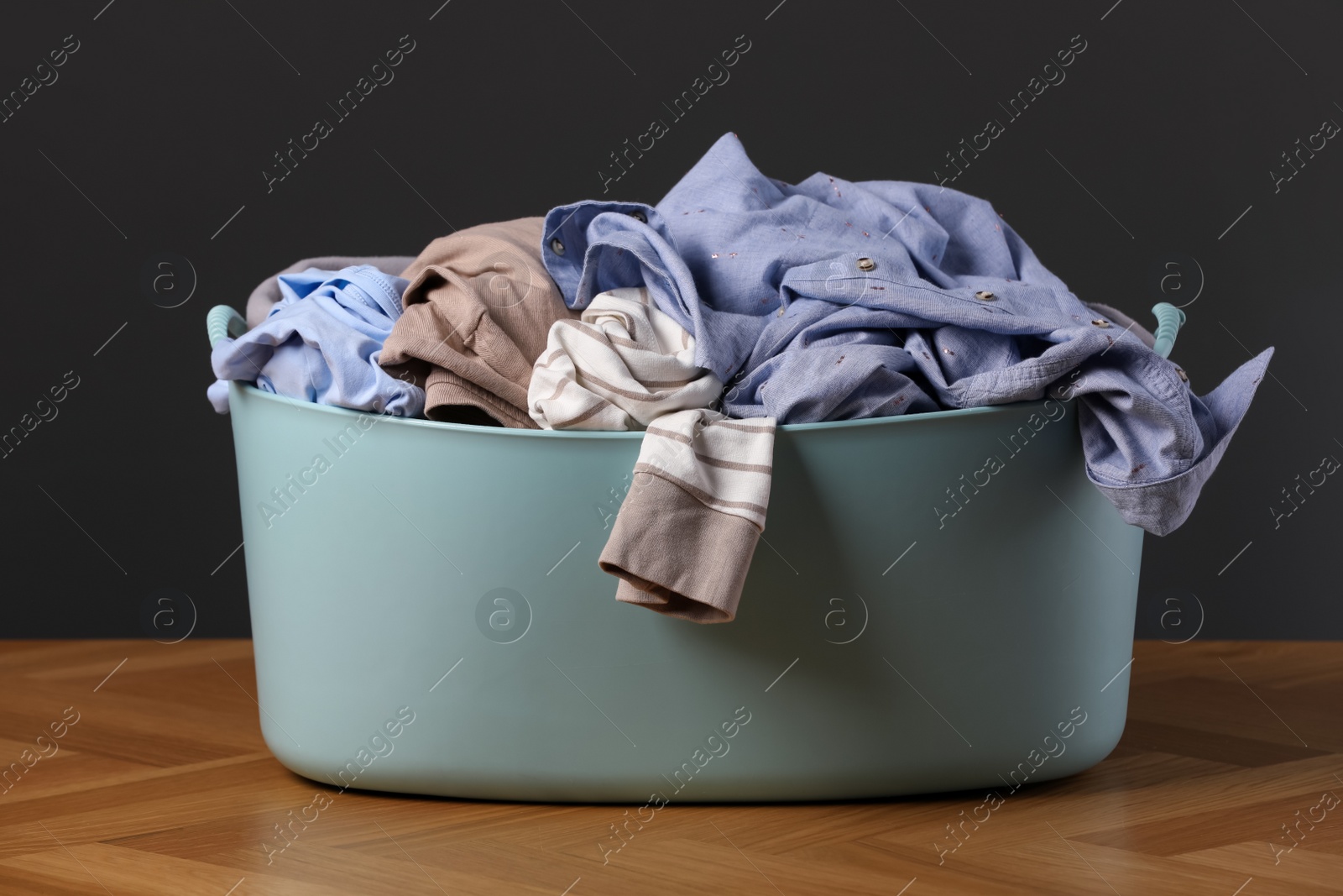 Photo of Laundry basket with clothes near dark grey wall