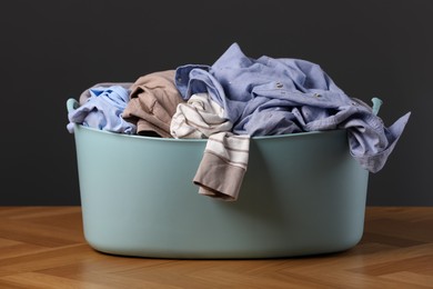 Photo of Laundry basket with clothes near dark grey wall