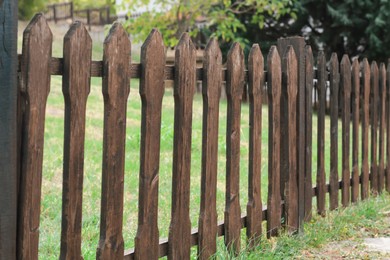 Low wooden fence near trees and green grass outdoors