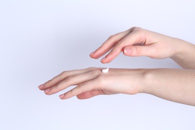 Photo of Woman applying cream on her hand against white background, closeup