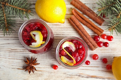 Flat lay composition with cranberry sauce in jars on white wooden background