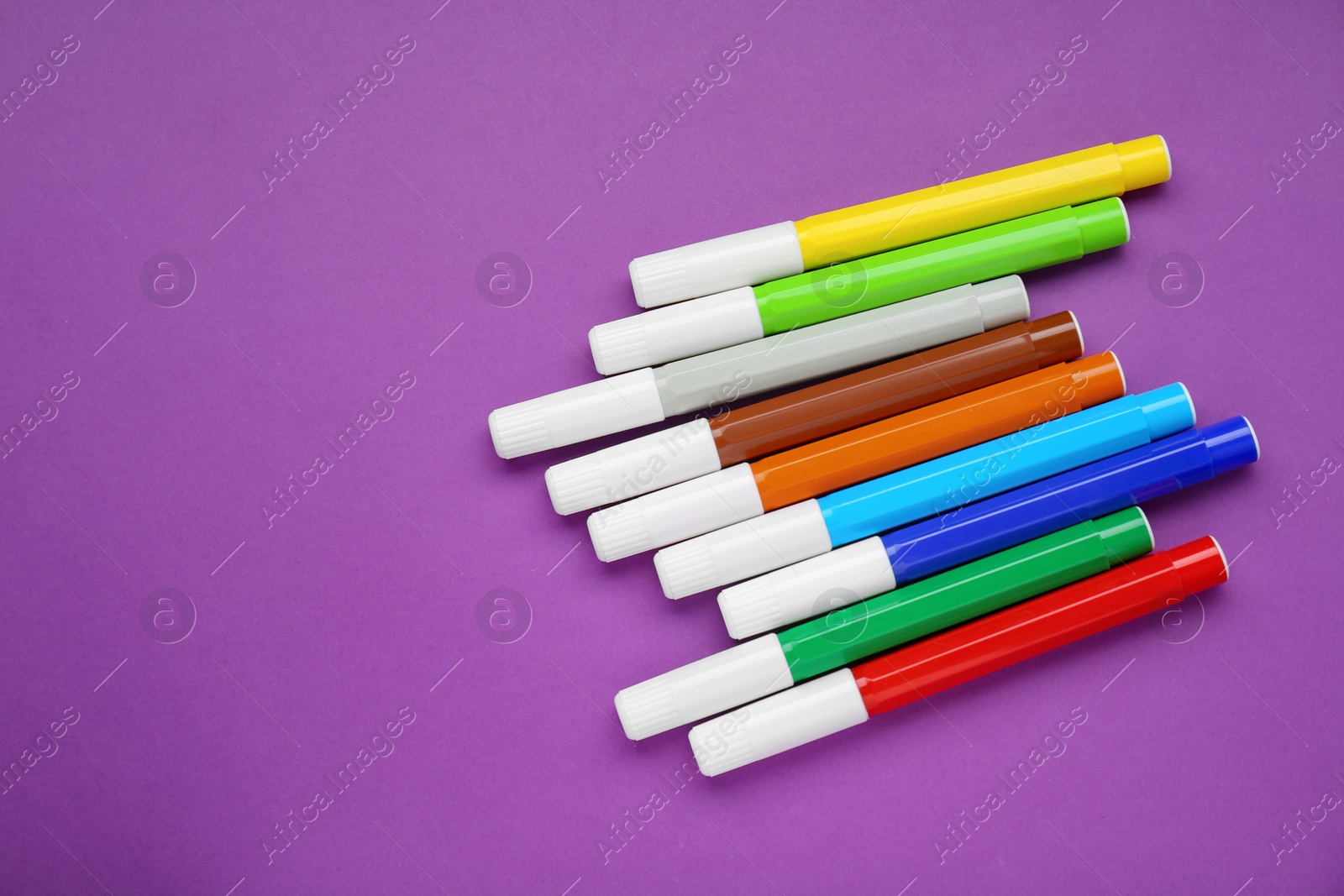 Photo of Different colorful markers on purple background, flat lay. Space for text