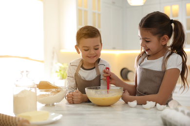 Photo of Cute little children cooking dough together in kitchen