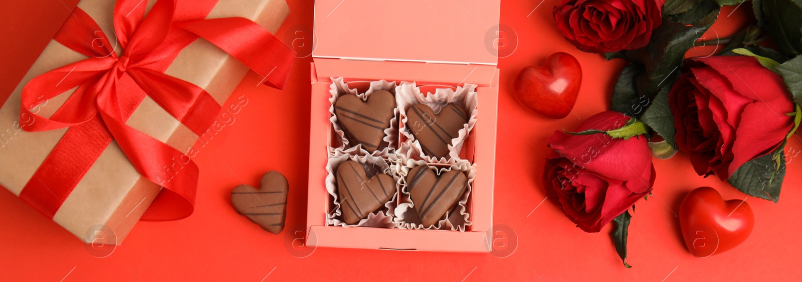 Photo of Flat lay composition with heart shaped chocolate candies on red background, space for text. Valentine's day celebration