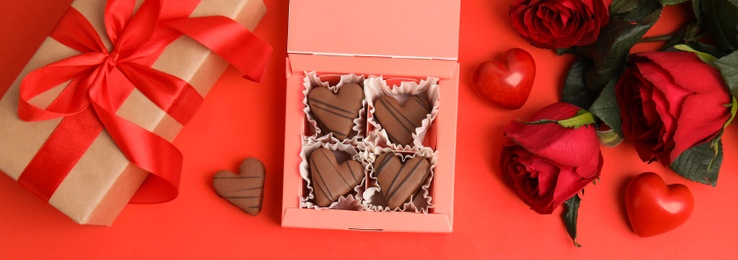 Flat lay composition with heart shaped chocolate candies on red background, space for text. Valentine's day celebration