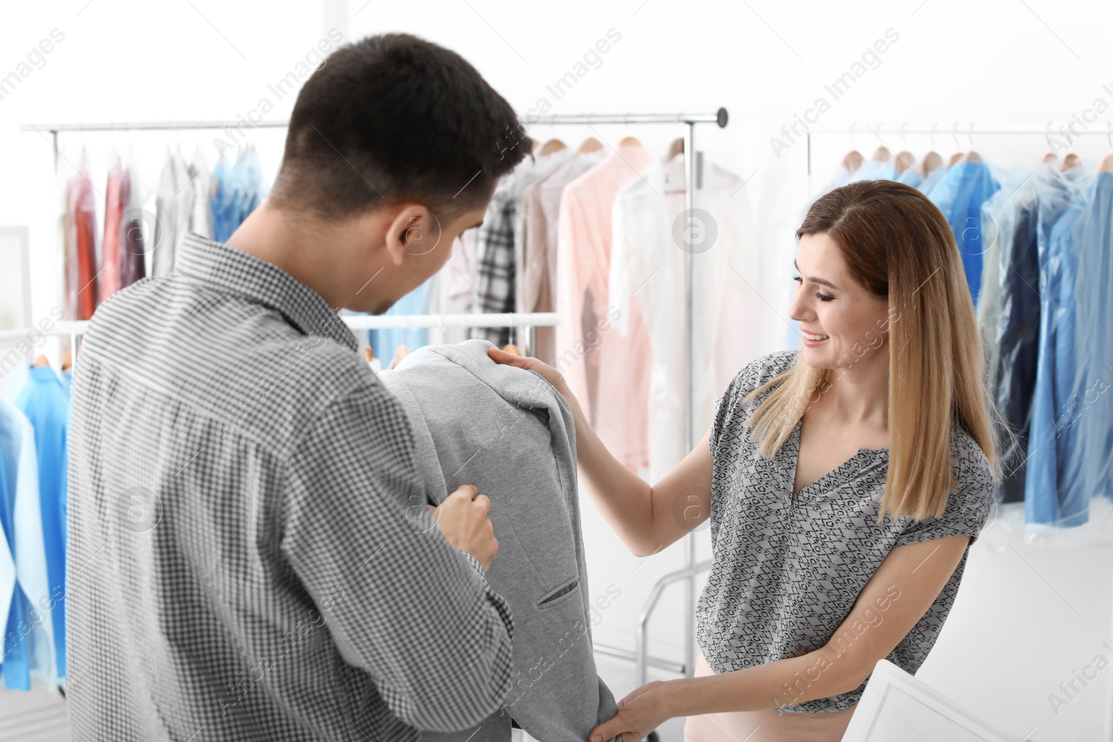 Photo of Young man giving jacket to dry-cleaner's worker